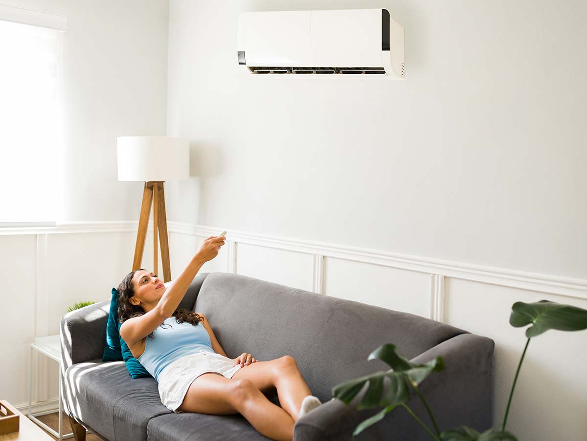 woman turns on ac from comfort of couch - Air Conditioning Repair and Installation In Bardstown, KY | Above All Mechanical