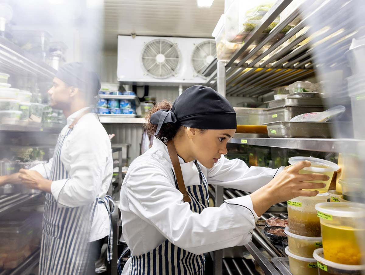 Latin American cooks working at a restaurant and looking for ingredients in the walk in refrigerator
