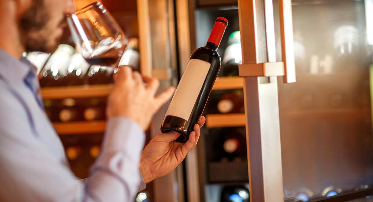 man checks wine that was stored in restaurant refrigerator.